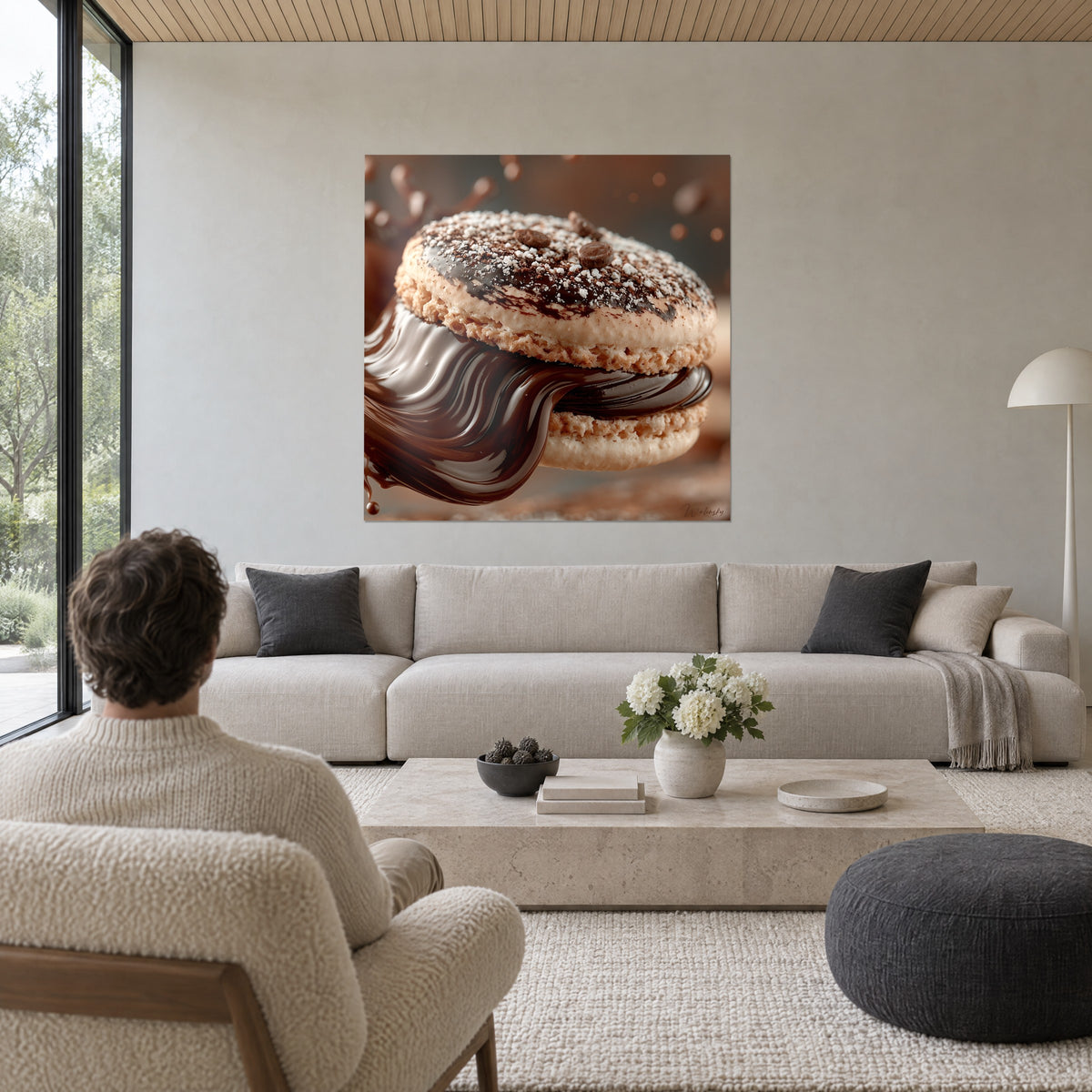 Cuadro macarón beige cubierto de ganache marrón fluida, azúcar glas en forma de nieve, sobre un sofá en un salón luminoso
