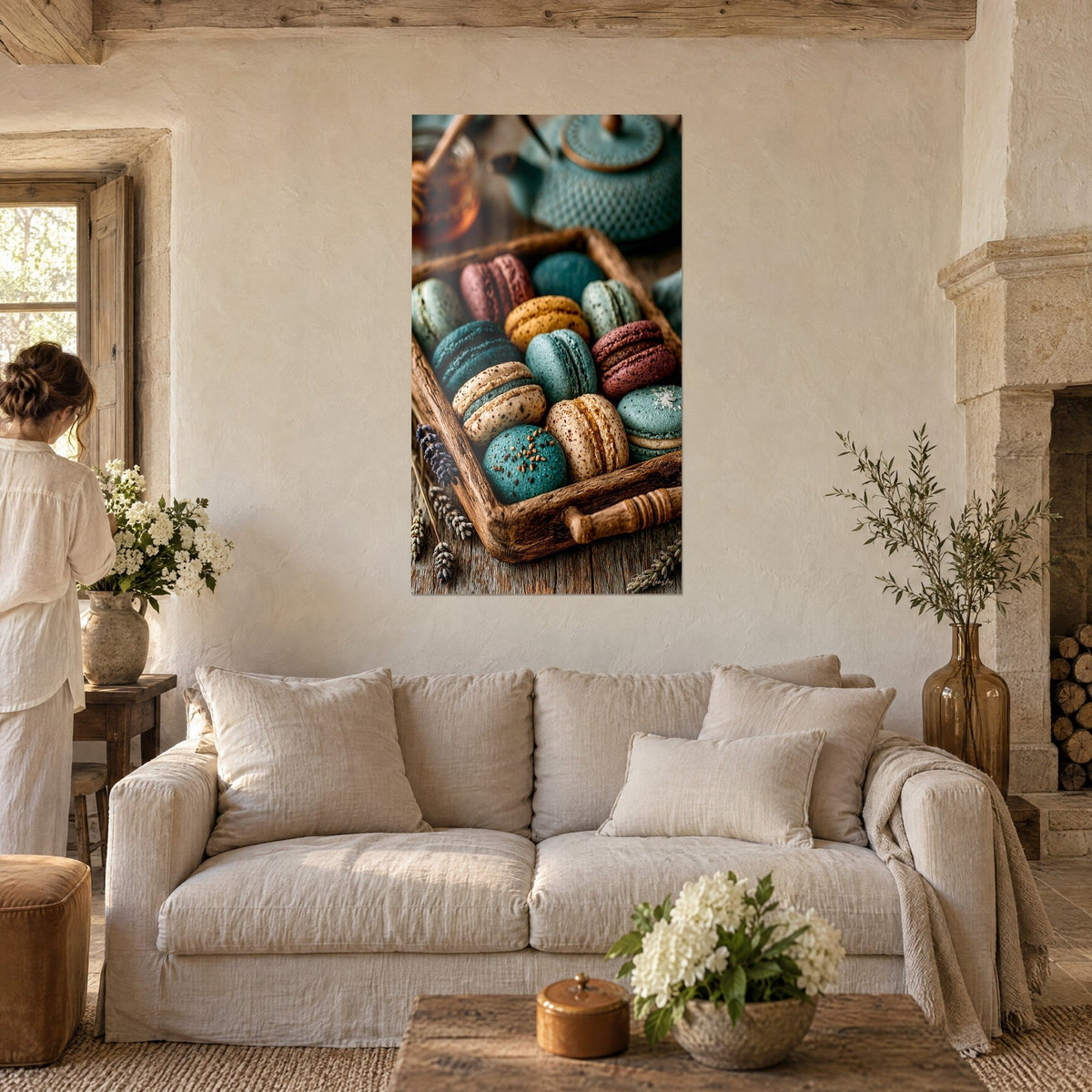 Quadro di macarons in blu petrolio e tonalità marroni su un vassoio rustico, teiera in ghisa verde, donna di spalle, sopra un divano in un soggiorno luminoso