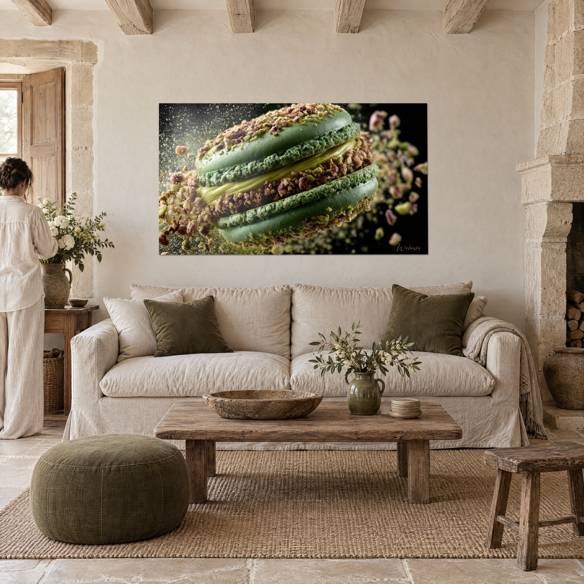 Wall art pistachio macaron with green shells and brown crumbs suspended in mid-air, seen from behind by a woman above a sofa in a bright living room