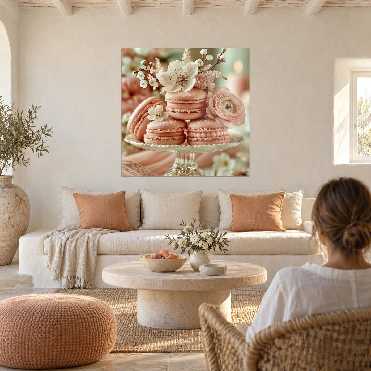 Tableau trois macarons roses couronnés d'une fleur blanche et d'un ranoncule pêche, au-dessus d'un canapé dans un salon lumineux
