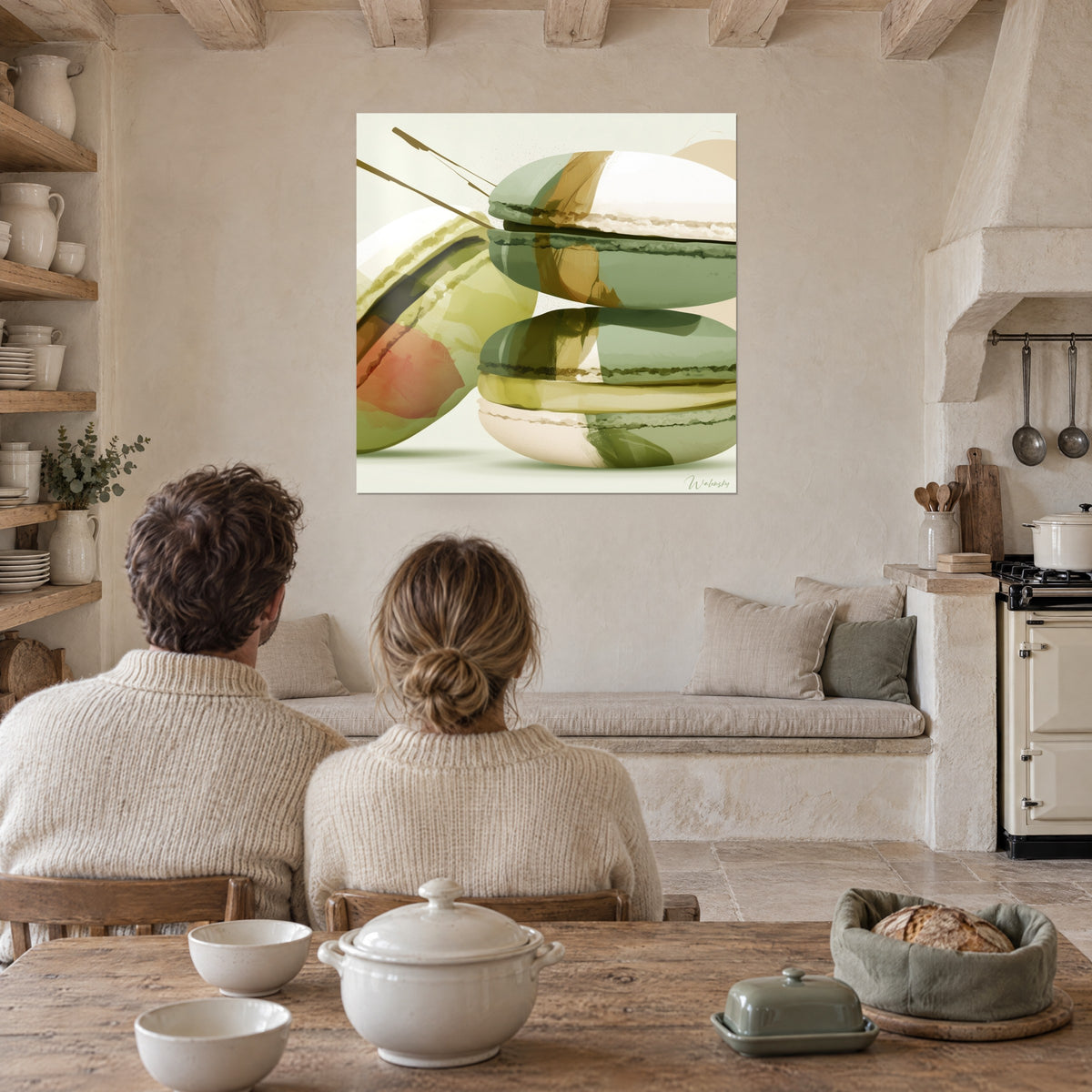 Quadro dolciumi pastello in verde oliva e ocra dorata, macchia corallo, di fronte a una coppia seduta al tavolo di una cucina in pietra