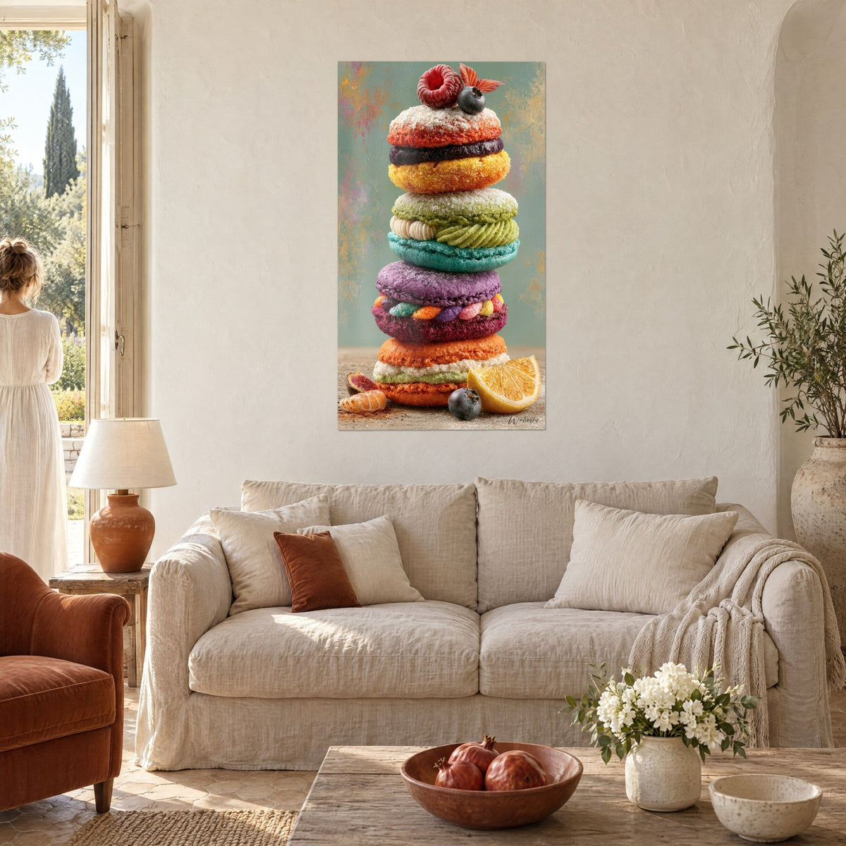 Tableau pile de macarons violet et turquoise coiffée d'une framboise, fond vert sauge, une femme de dos, au-dessus d'un canapé dans un salon lumineux