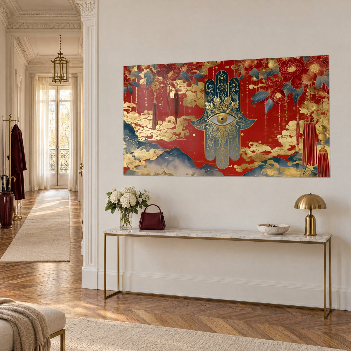 Tableau amulette hamsa ornée sur fond rouge, pompons pourpres suspendus et nuées dorées, console laitonnée dans une entrée haussmannienne