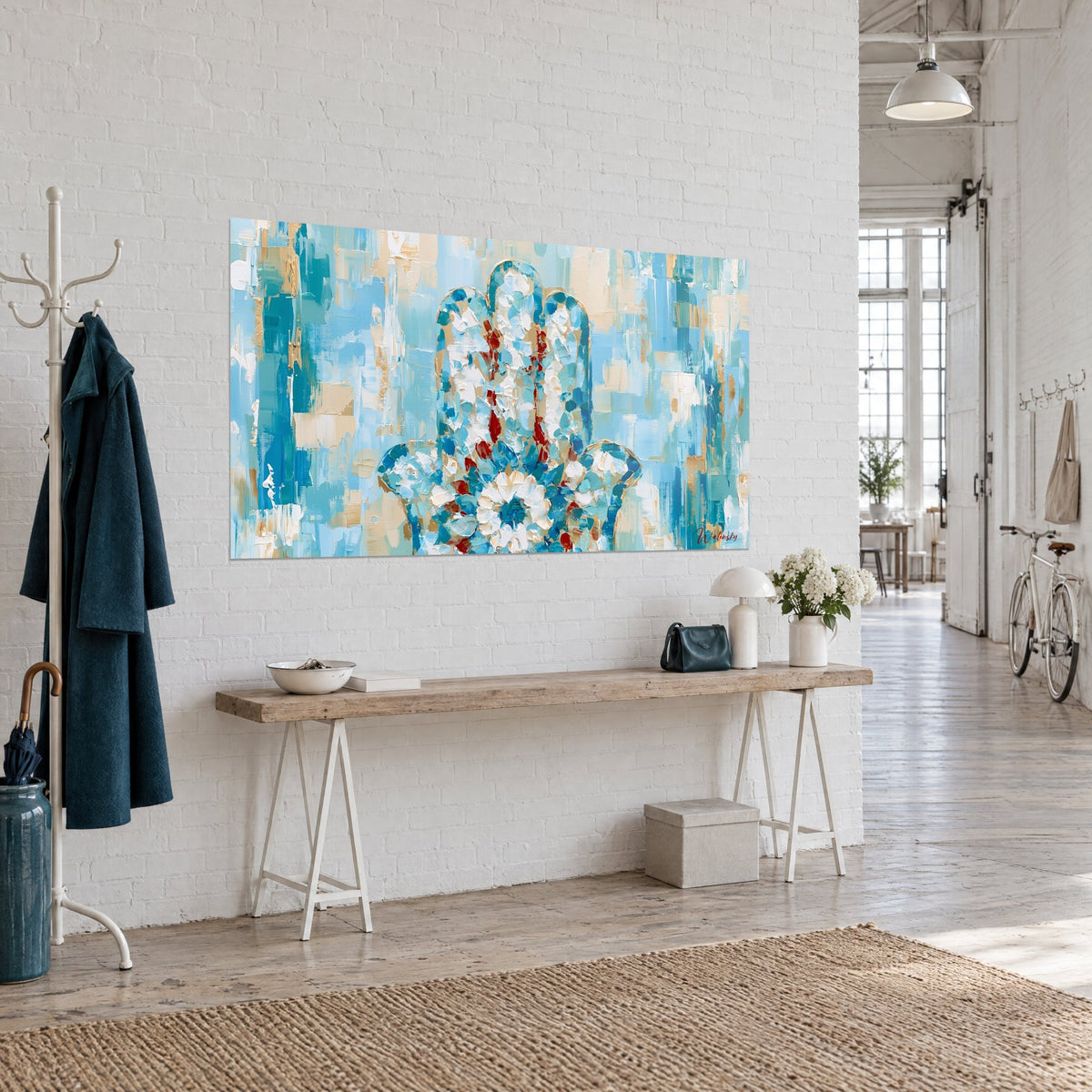 Tableau amulette hamsa en mosaïque de bleu glacier et crème, fleur blanche centrale, sur mur de briques blanches de loft d'artiste