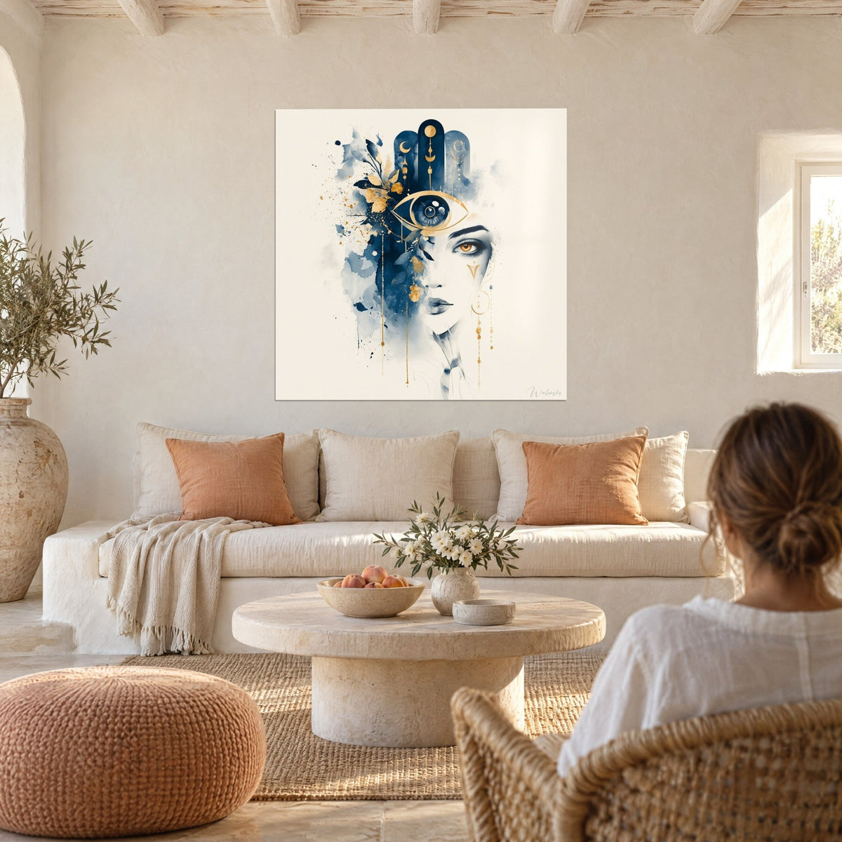 Tableau hamsa marine et or fusionné à un visage de femme, regard ambré, au-dessus d'un canapé dans un salon lumineux