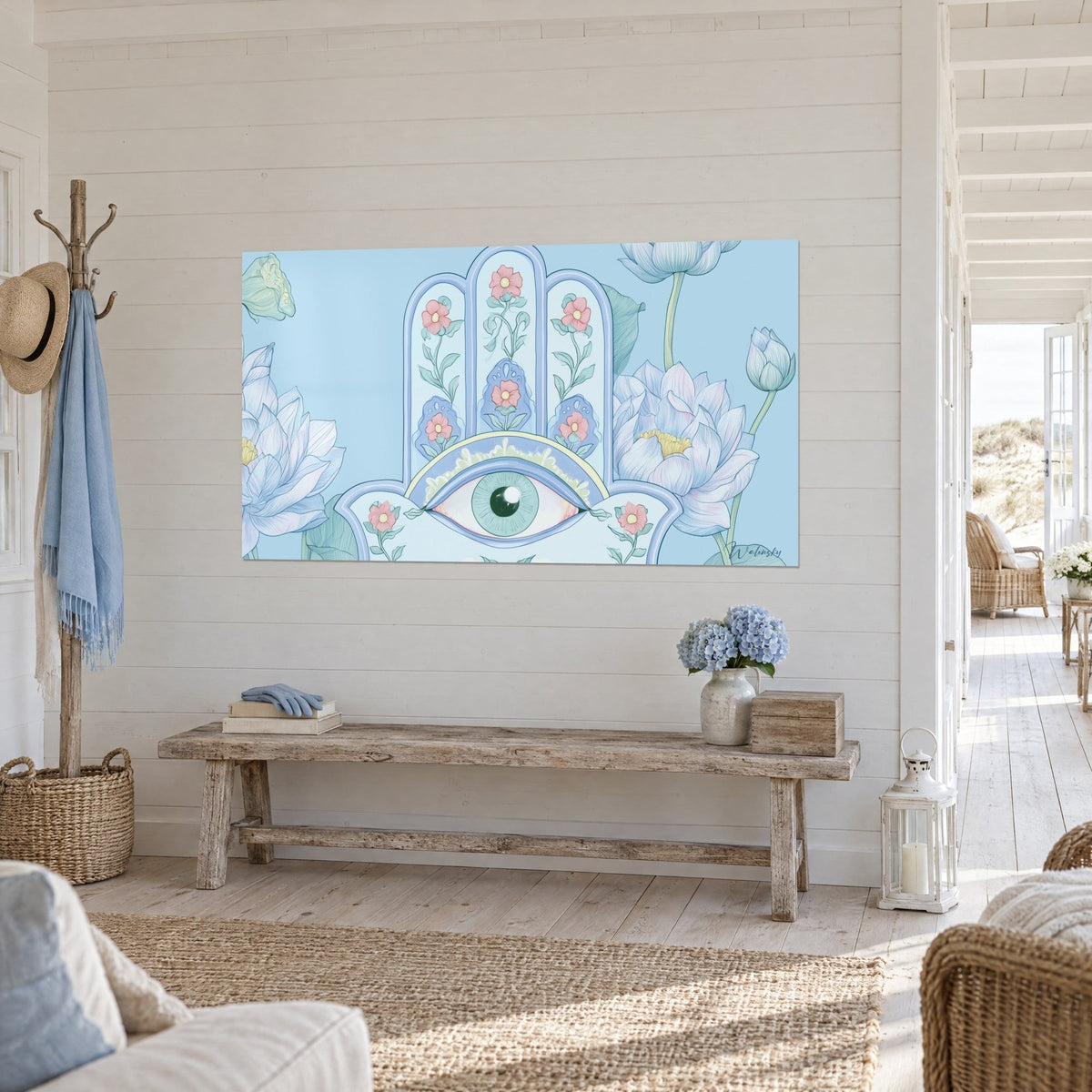 Cuadro talismán hamsa con iris verde almendra, flores rosa coral sobre fondo azul cielo, pared blanca de listones junto a una consola