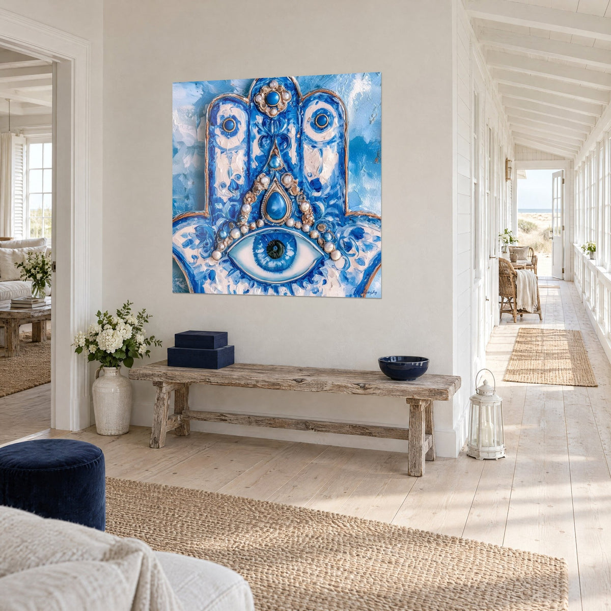 Tableau talisman main de Fatma, empâtements bleu roi et blanc, joyaux nacrés, sur un mur blanc au bout d'un couloir clair