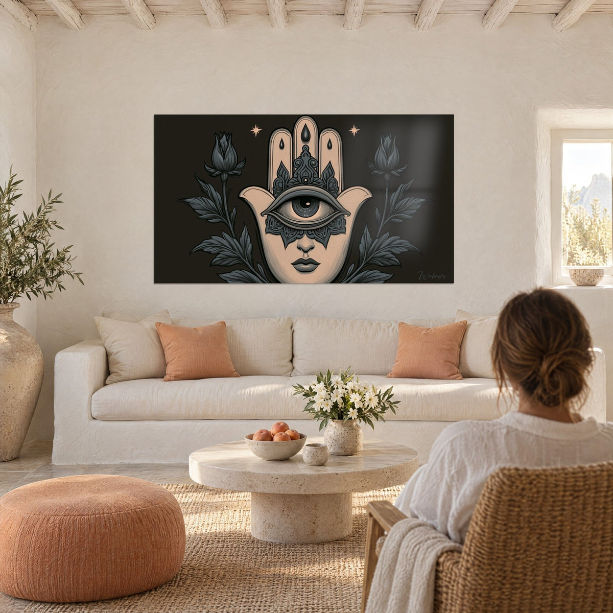 Cuadro mano de Fatma en beige con ojo central gris, rodeada de rosas antracita sobre fondo negro, encima de un sofá en un salón luminoso