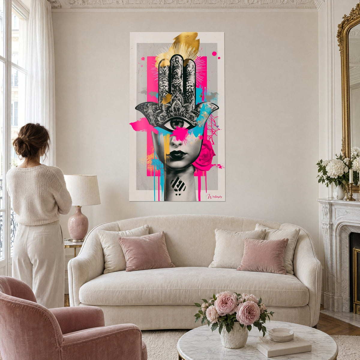 Tableau amulette hamsa ciselée sur visage de femme, rose fuchsia et or, aplat gris perle, au-dessus d'un canapé dans un salon lumineux
