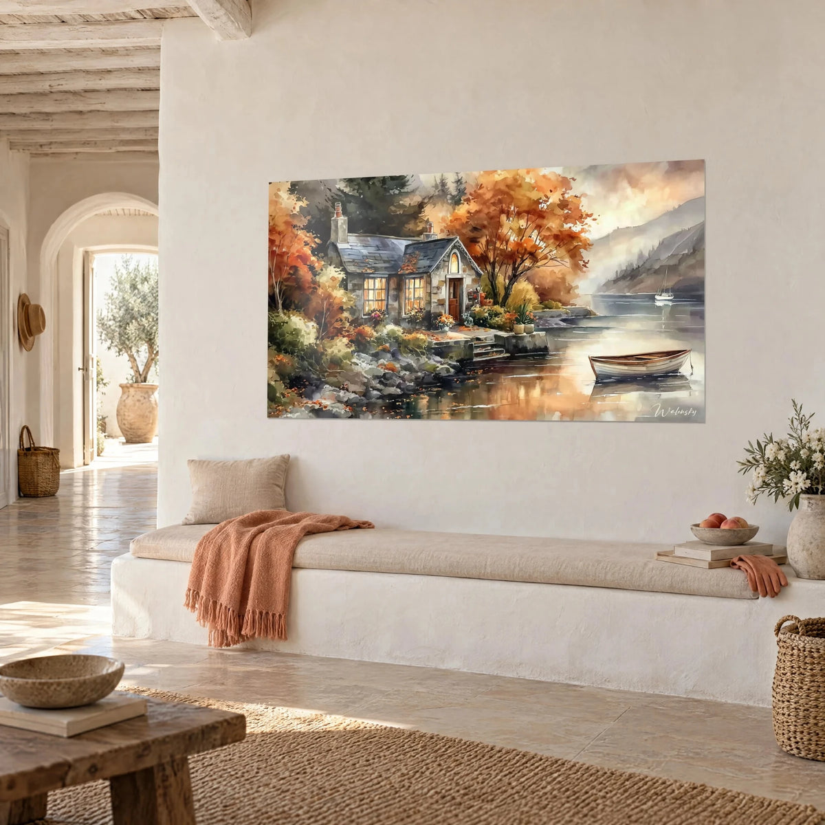 Wall art cottage with a blue-grey slate roof surrounded by russet foliage, white sailboat in the distance, hung in three-quarter view in a bright lounge