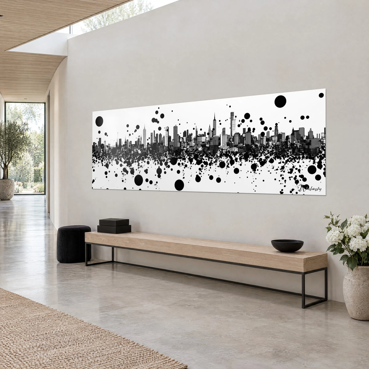 Quadro silhouette di Manhattan tracciata a inchiostro, torri grigie e macchie nere su fondo bianco, parete beige e panca in legno chiaro