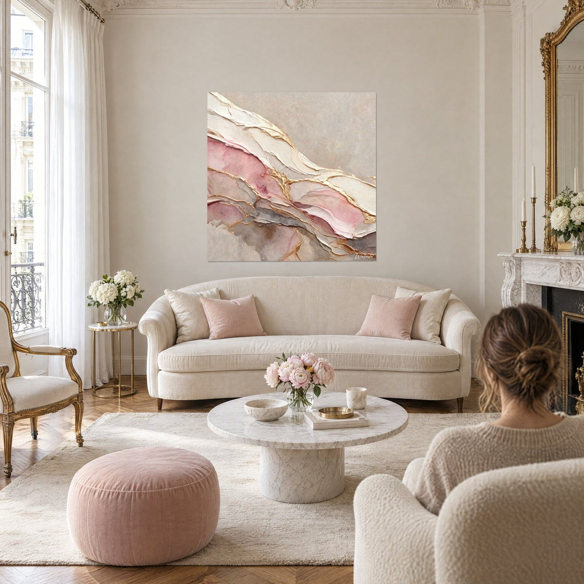 Tableau strates de marbre rose et ivoire cernées de veines dorées, femme de dos, au-dessus d'un canapé dans un salon lumineux