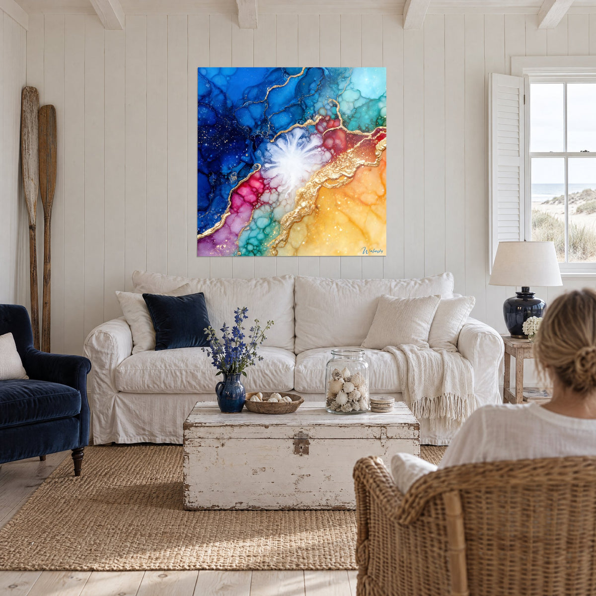 Tableau explosion marbrée bleu cobalt et or, cœur blanc rayonnant, veines dorées, une femme de dos, au-dessus d'un canapé dans un salon lumineux