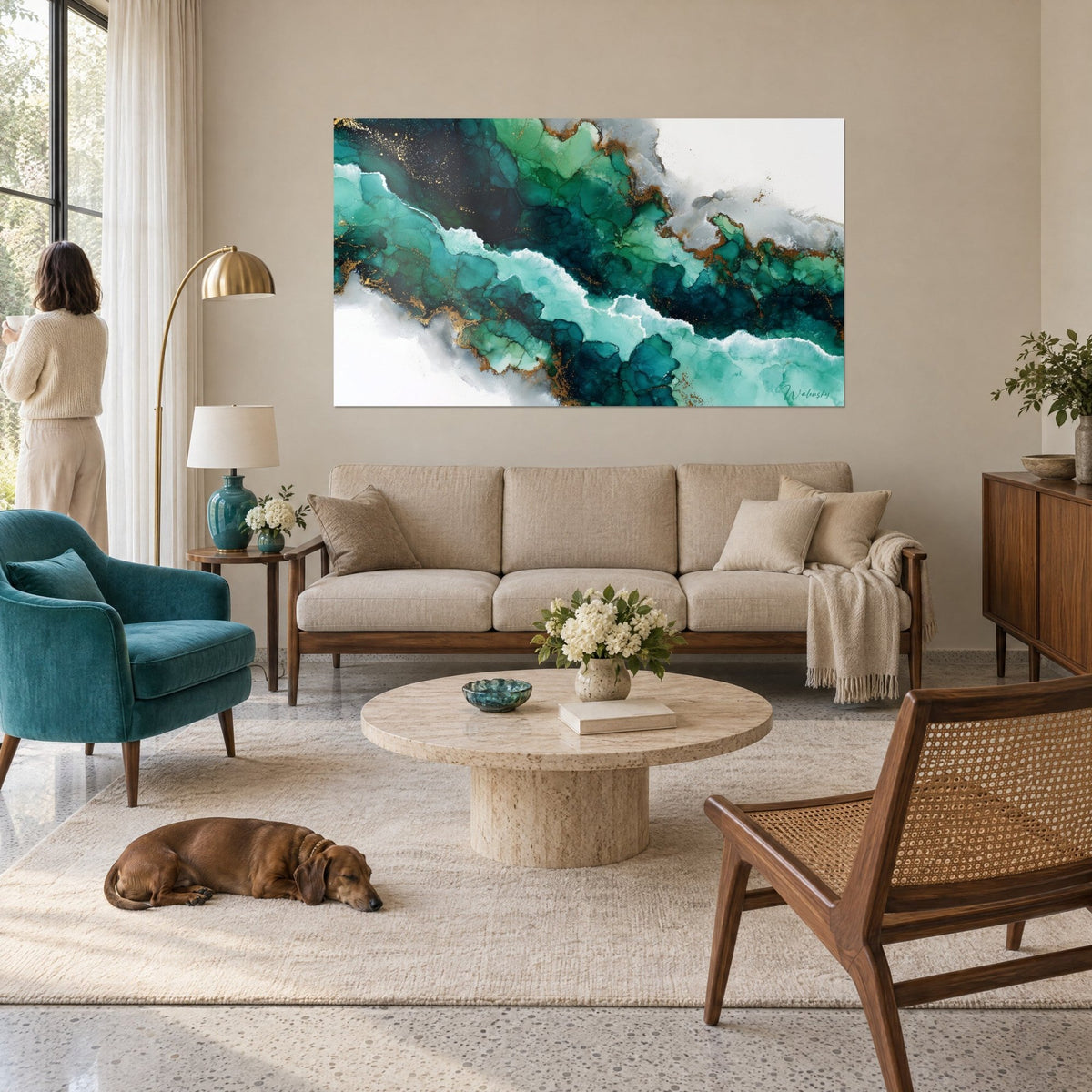 Schilderij vloeiende marmering in smaragd en turquoise met gouden aders, bekeken door een vrouw van achteren, boven een bank in een lichte woonkamer