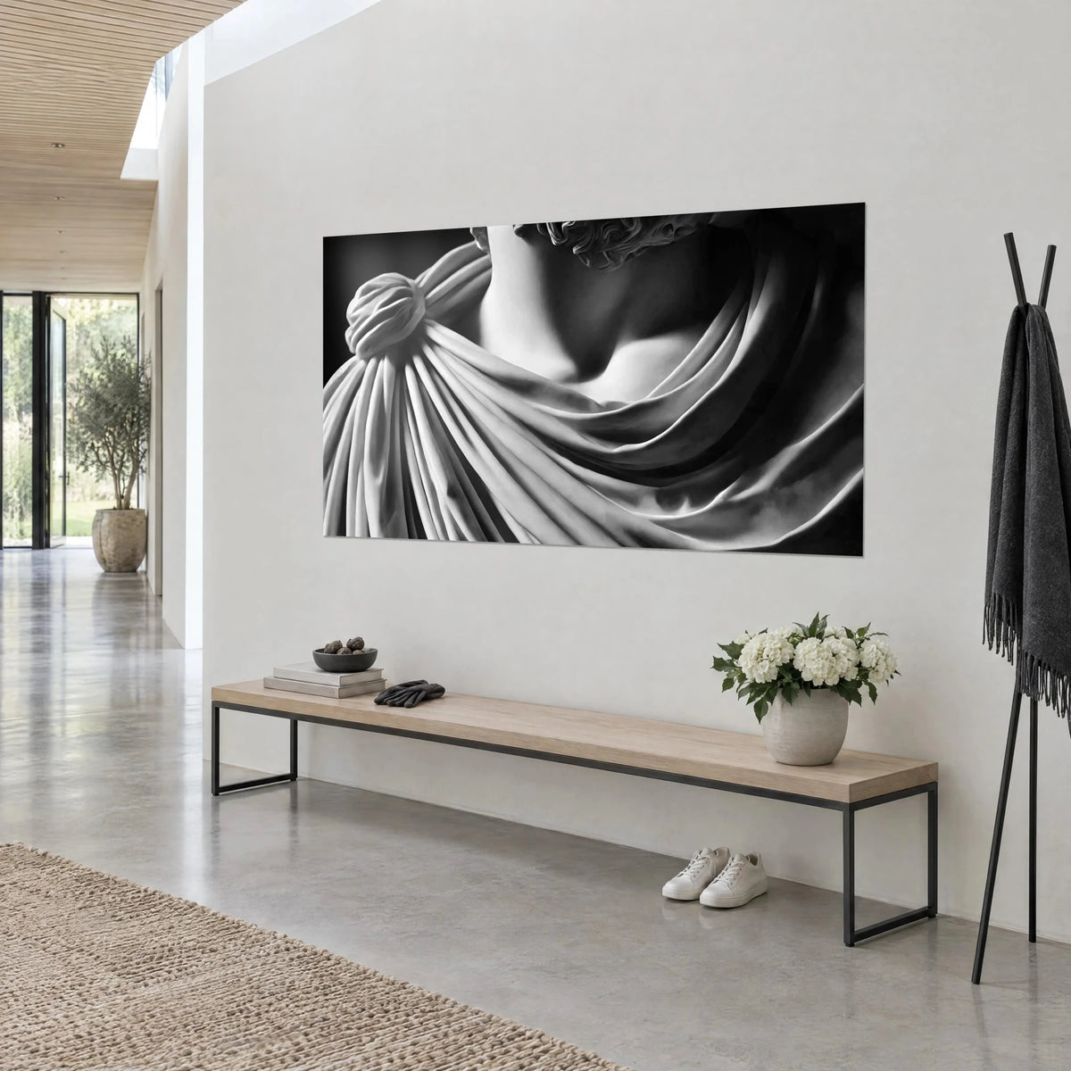Cuadro estatua antigua con pliegues de mármol gris perla y negro profundo, nudo de hombro redondeado, sobre una pared blanca de casa de arquitecto