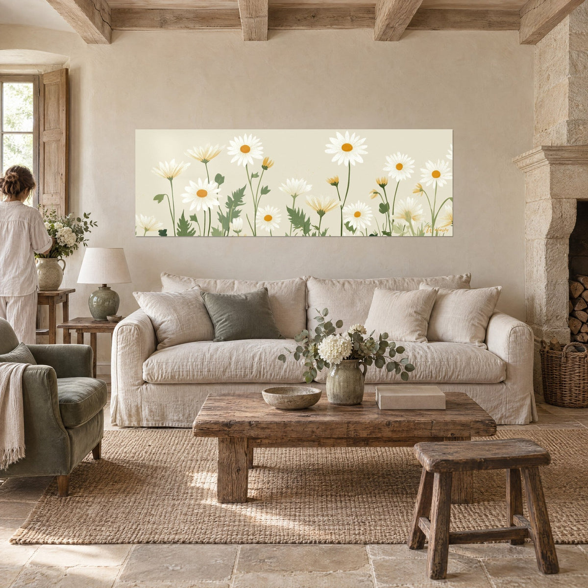 Wall art white daisies with ochre centers on cream background, green stems, a woman seen from behind, above a sofa in a bright living room