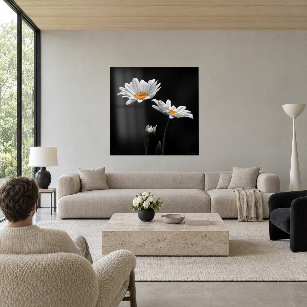 Tableau deux marguerites blanches au cÅur orangé sur fond noir, au-dessus d'un canapé dans un salon lumineux