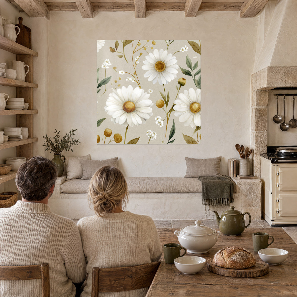 Quadro boccioli dorati rotondi e margherite color crema, foglie verde intenso su fondo sabbia, di fronte a un tavolo da cucina in legno