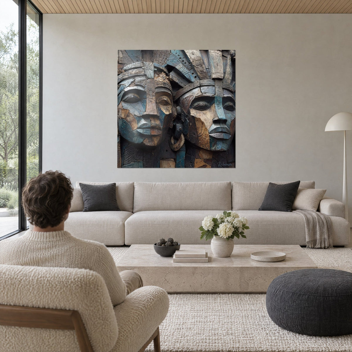 Quadro di volti africani scolpiti nel legno, turchese e ocra, due profili affiancati sopra un divano in un soggiorno luminoso