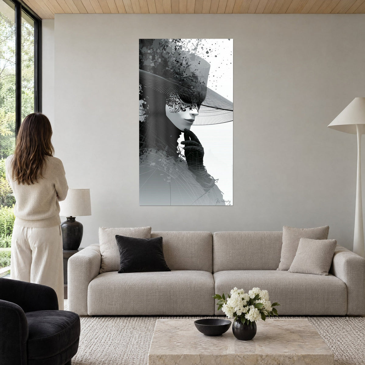 Wall art Venetian mask with black lace under a wire-mesh hat, grey and white, above a sofa in a bright living room