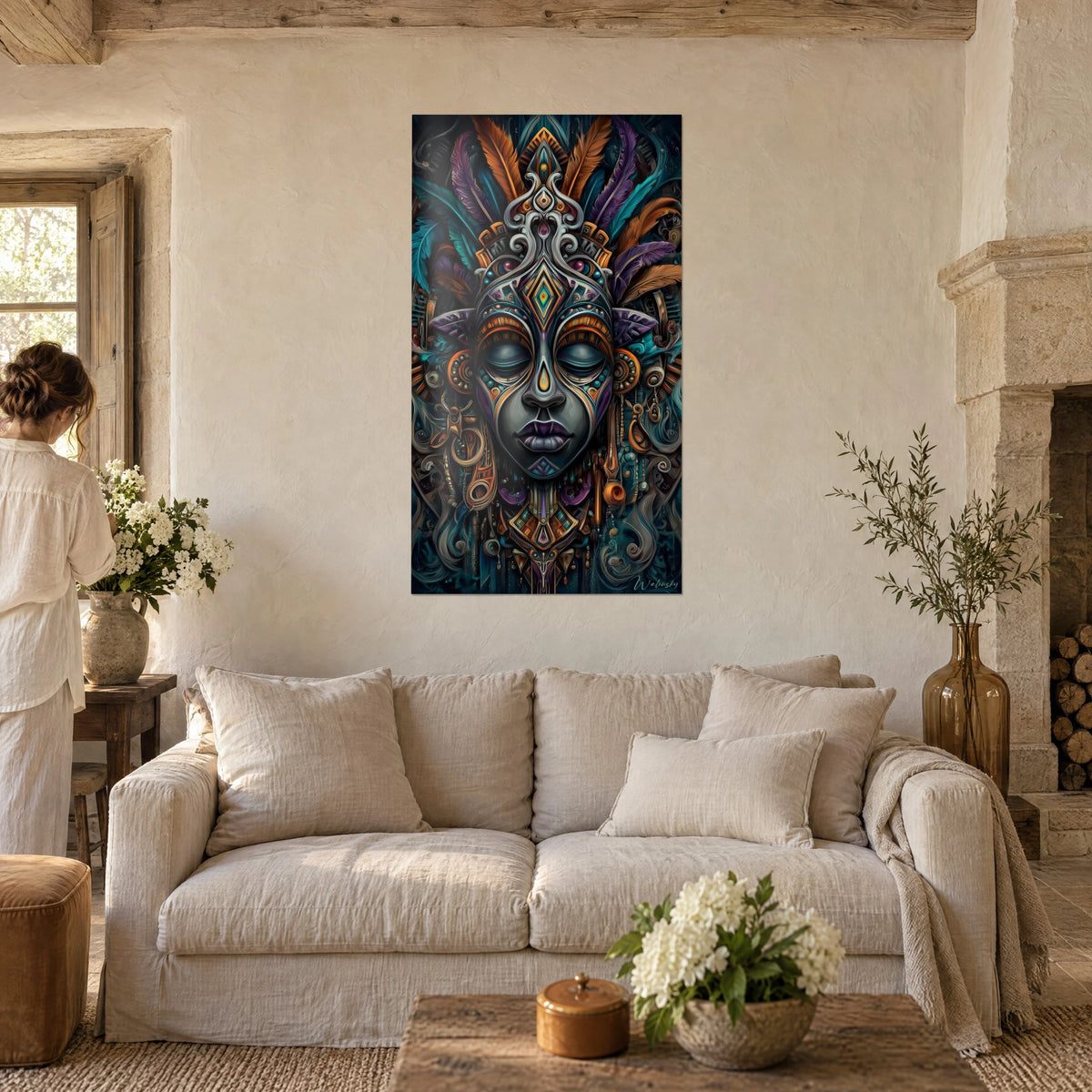 Tableau masque africain aux paupières closes, plumes turquoise et orange, visage gris ardoise, au-dessus d'un canapé dans un salon lumineux