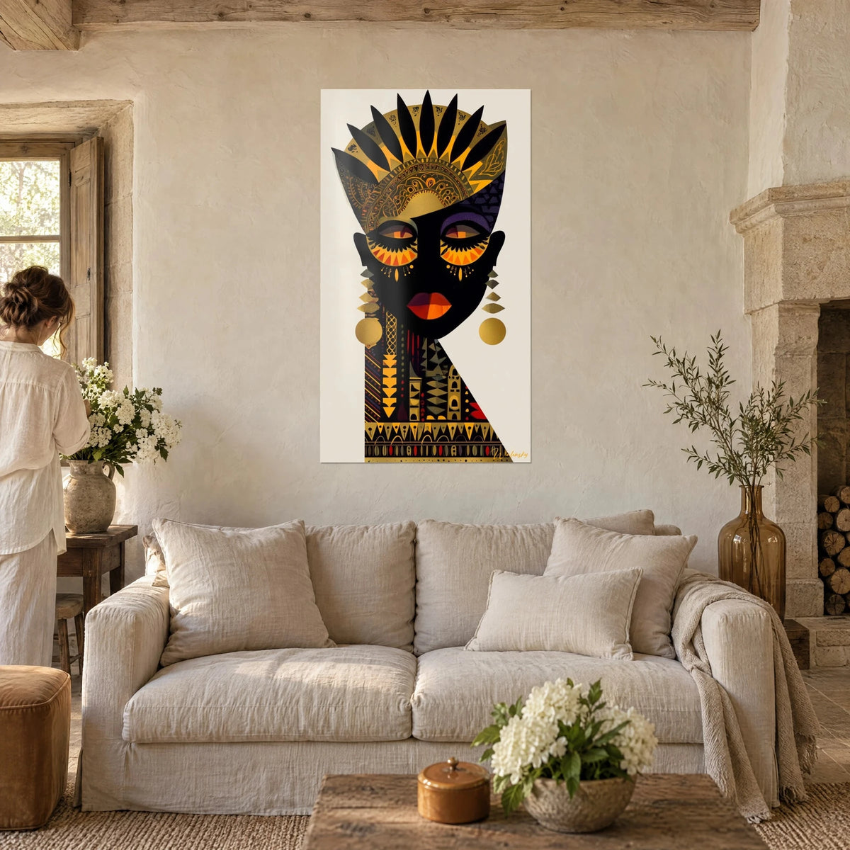 Quadro maschera africana nera con copricapo di piume dorate, labbra arancio-rosso, lungo collana ocra; sopra un divano in un soggiorno luminoso