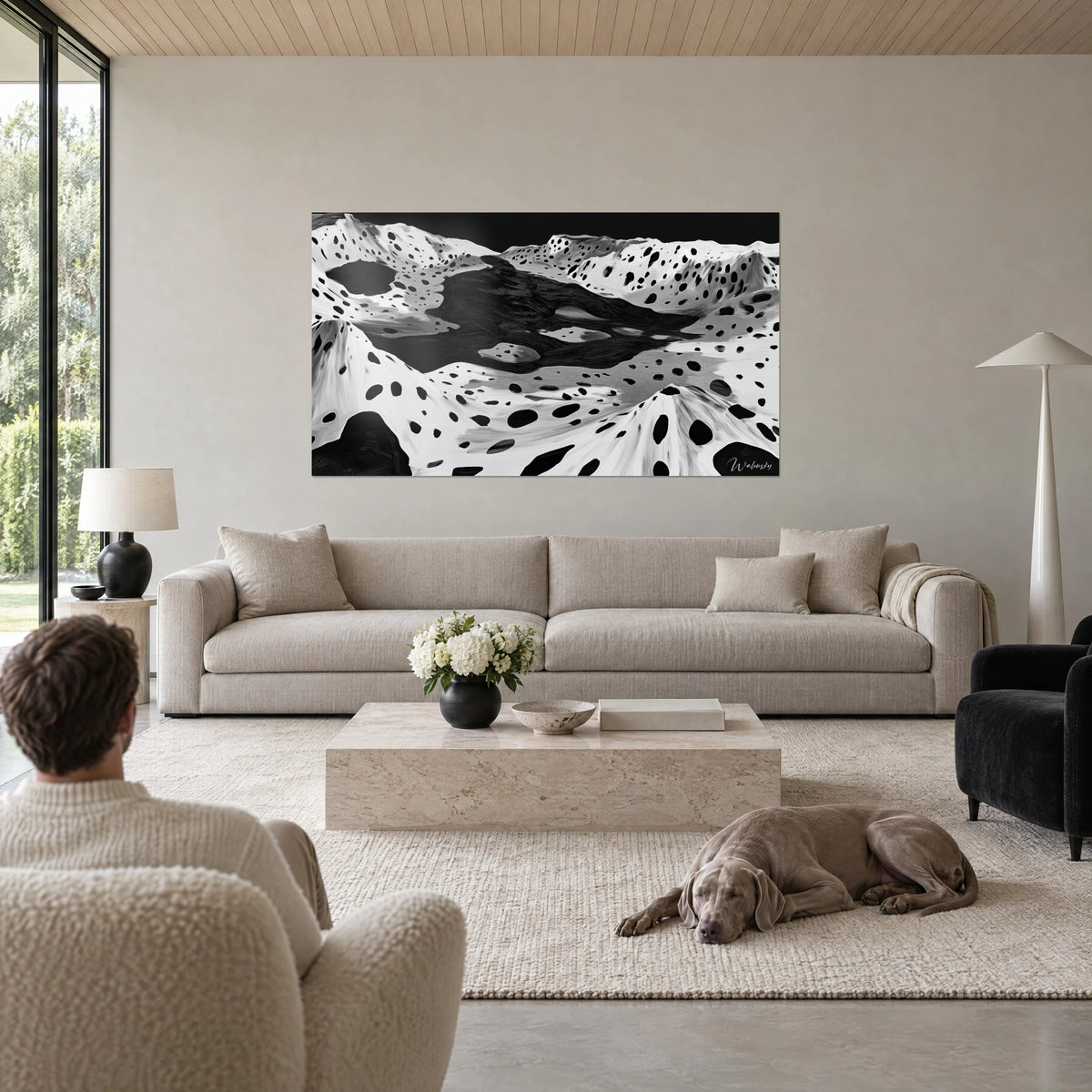 Cuadro relieve lunar moteado en blanco y negro, lago de tinta oscuro entre crestas salpicadas, encima de un sofá en un salón luminoso