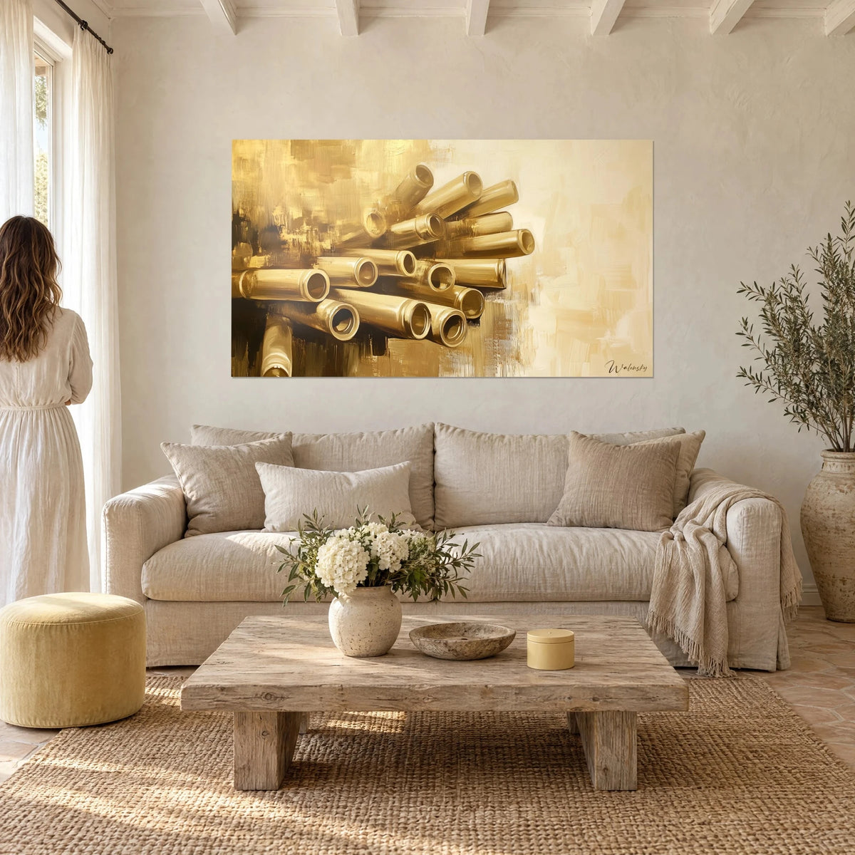 Tableau faisceau de tubes dorés sur fond crème, touches d'ocre brun, femme de dos, au-dessus d'un canapé dans un salon lumineux