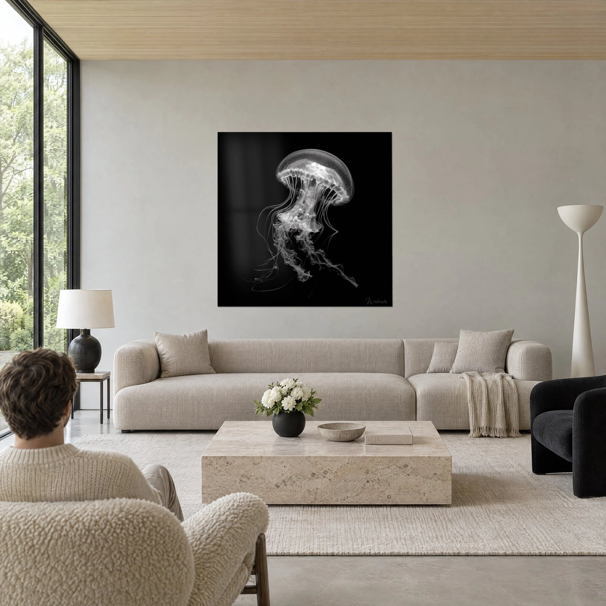 Tableau méduse translucide aux tentacules de dentelle blanche sur fond noir, homme de dos, au-dessus d'un canapé dans un salon lumineux