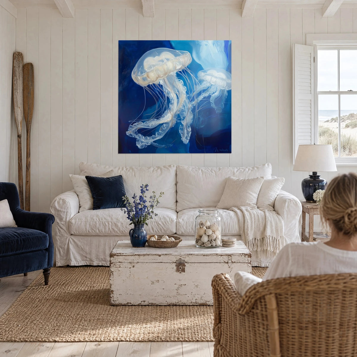 Quadro medusa trasparente dai tentacoli diafani, blu cobalto e bianco perlato, sopra un divano in un soggiorno luminoso