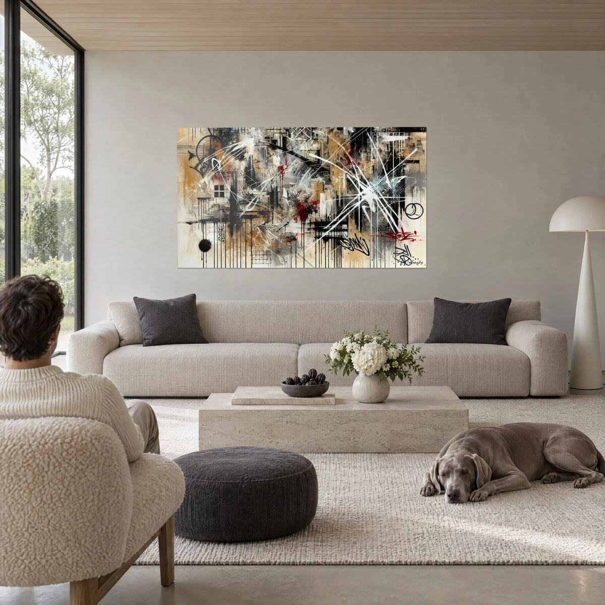 Gemälde urbanes abstraktes Fresko mit schwarzen Laufspuren, karmesinroten und sandbeigen Spritzern, über einem Sofa in einem hellen Wohnzimmer