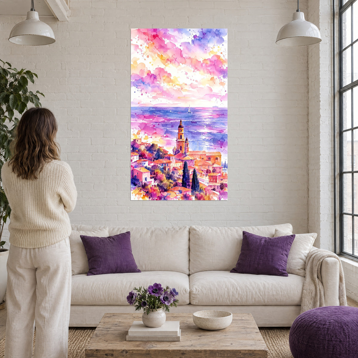 Cuadro campanario ocre de Menton bajo un cielo rosa y amarillo, mar violeta, sobre un sofá en un salón luminoso