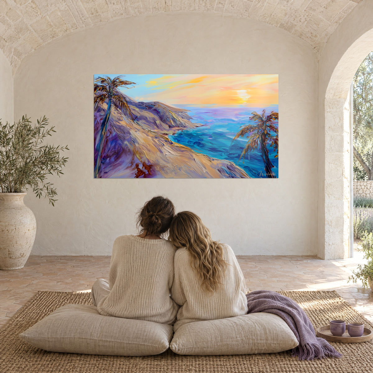 Schilderij van een oranje zonsondergang boven een turquoise zee en een lila duin, twee palmbomen, tegenover een stel zittend op witte kussens