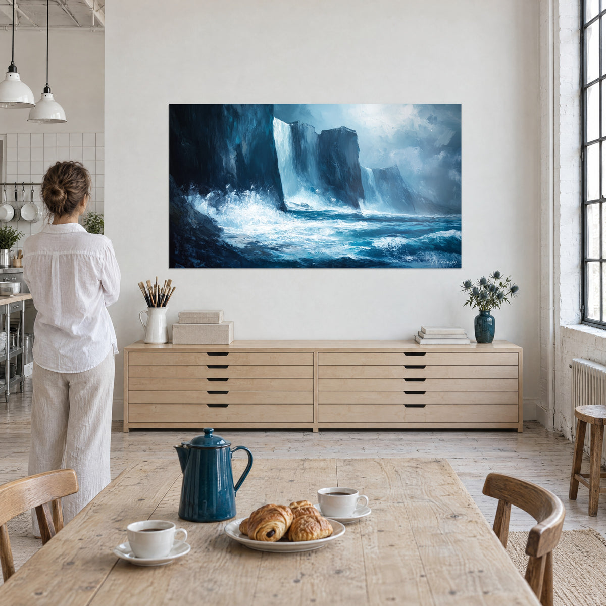 Tableau océan furieux fracassé contre des falaises noires, écume blanche et bleu pétrole, une femme de dos près d'une table