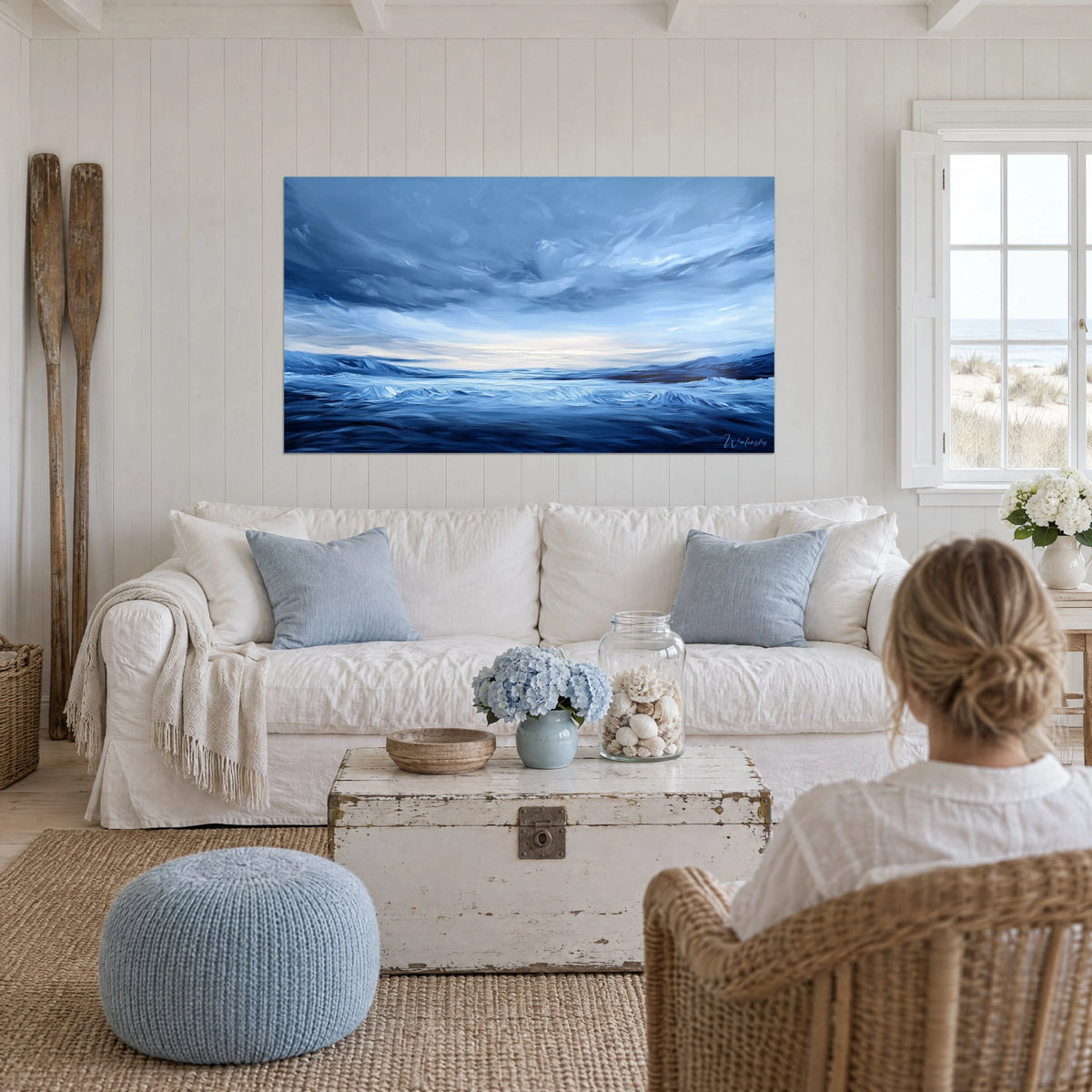 Quadro onda d'inchiostro sotto un cielo di tempesta, blu notte e bianco perlato, una donna di spalle sopra un divano in un soggiorno luminoso