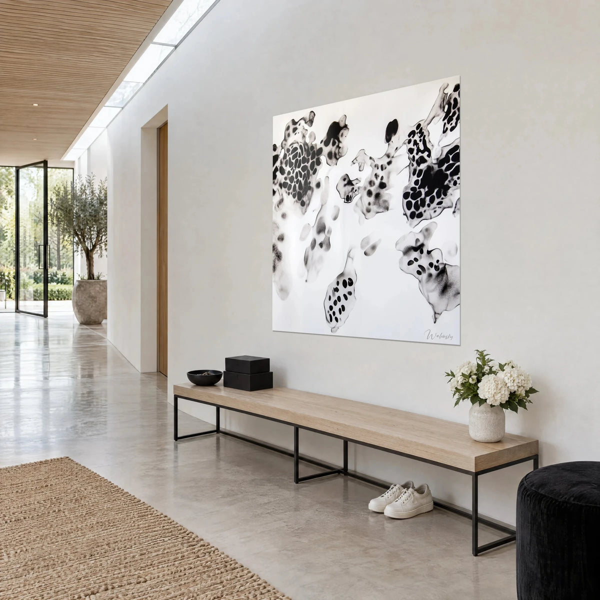 Tableau amas cellulaires tachetés noir et gris pâle, motifs en galets sur blanc pur, accroché dans un couloir clair, vue de trois-quarts