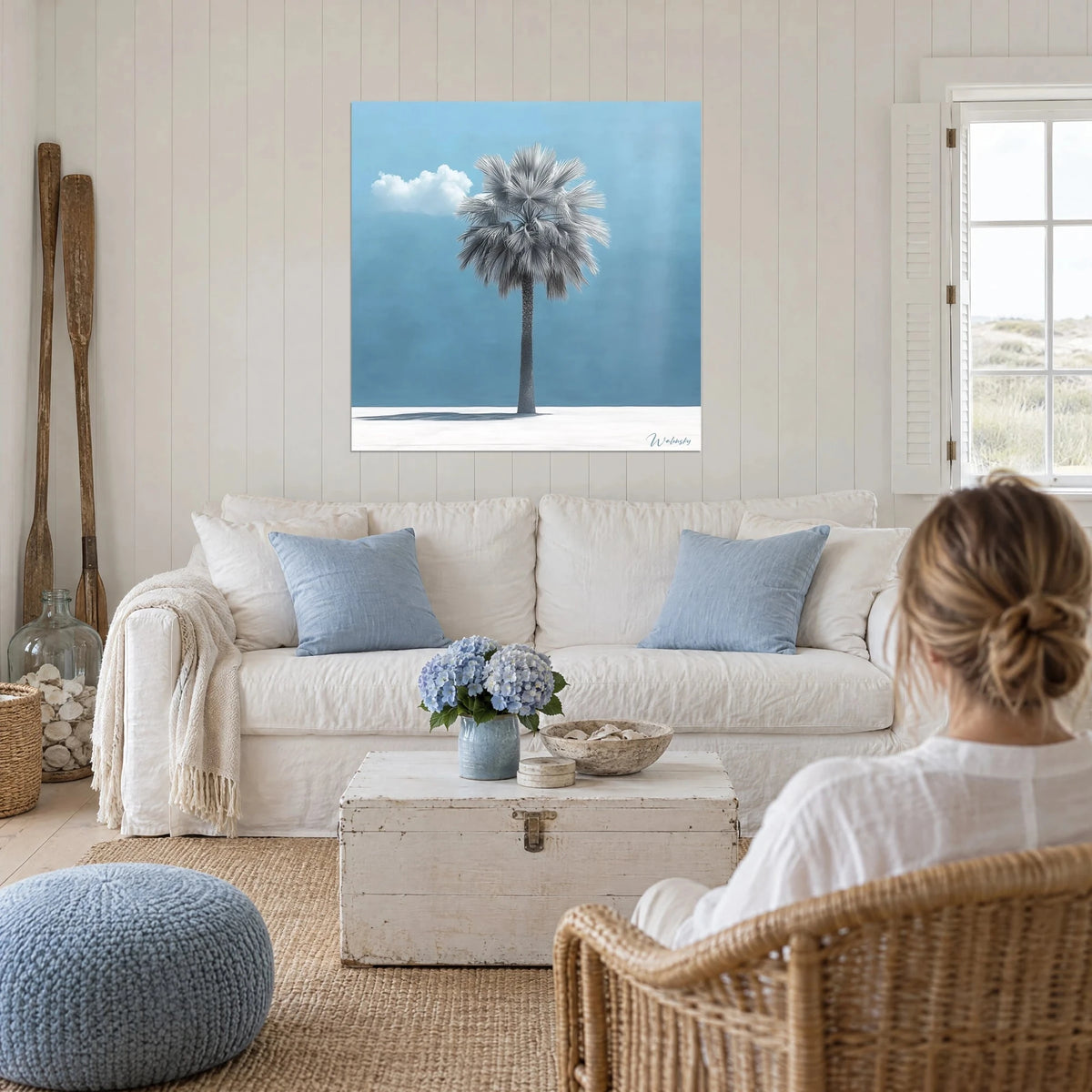 Quadro palma a ventaglio con foglie argentate su cielo azzurro, nuvola bianca, sopra un divano in un soggiorno luminoso
