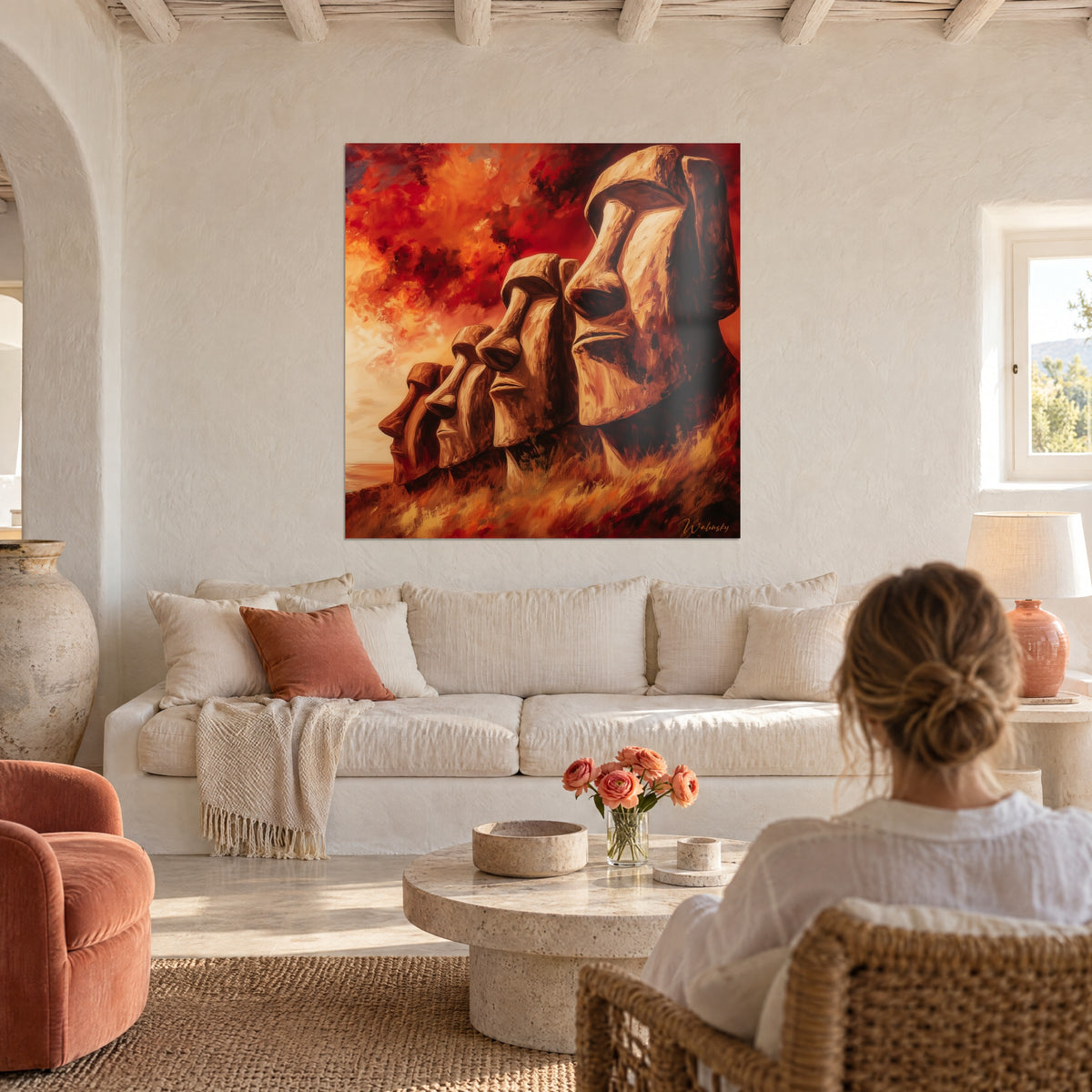 Tableau statues géantes de l'île de Pâques, ciel rouge et orange, une femme de dos, au-dessus d'un canapé dans un salon lumineux