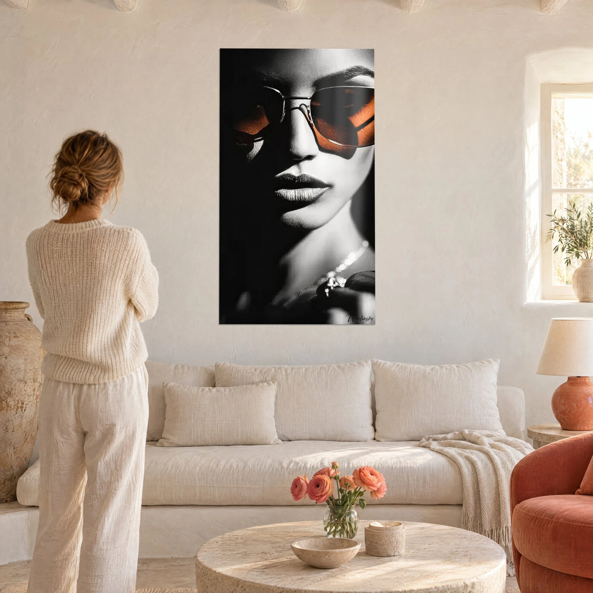 Cuadro retrato glamuroso en blanco y negro, gafas cobrizas y collar de perlas, encima de un sofá en un salón luminoso