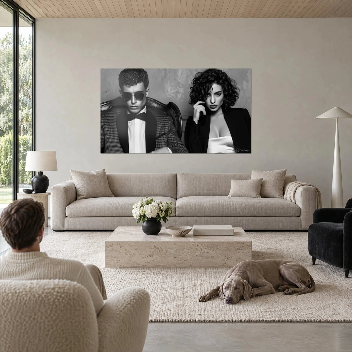 Quadro coppia elegante in bianco e nero, uomo con occhiali da sole scuri e papillon, bruna riccia, sopra un divano in un soggiorno luminoso