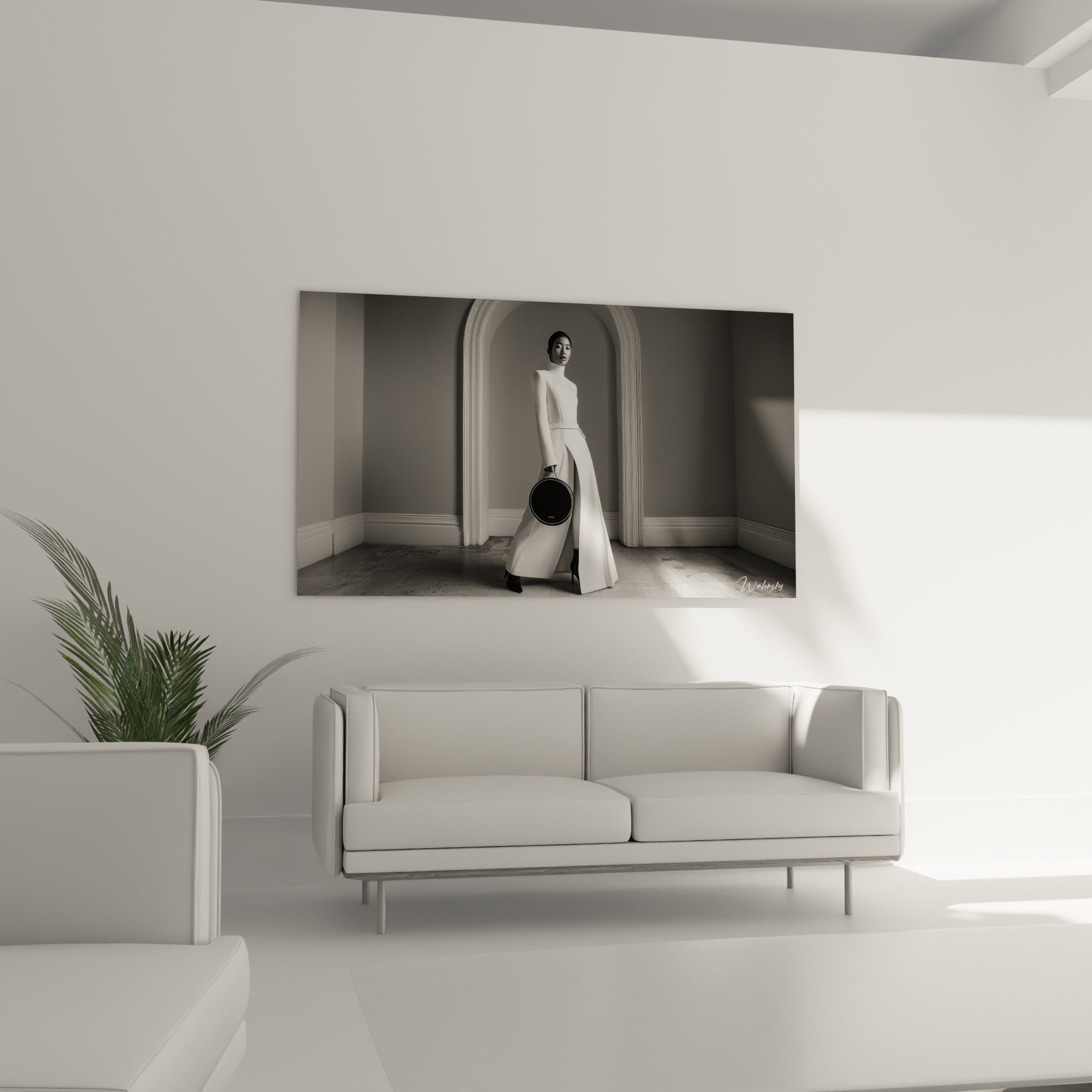 Femme en robe blanche traversant un hall gris, sac noir en main, au-dessus d'un canapé dans un salon lumineux