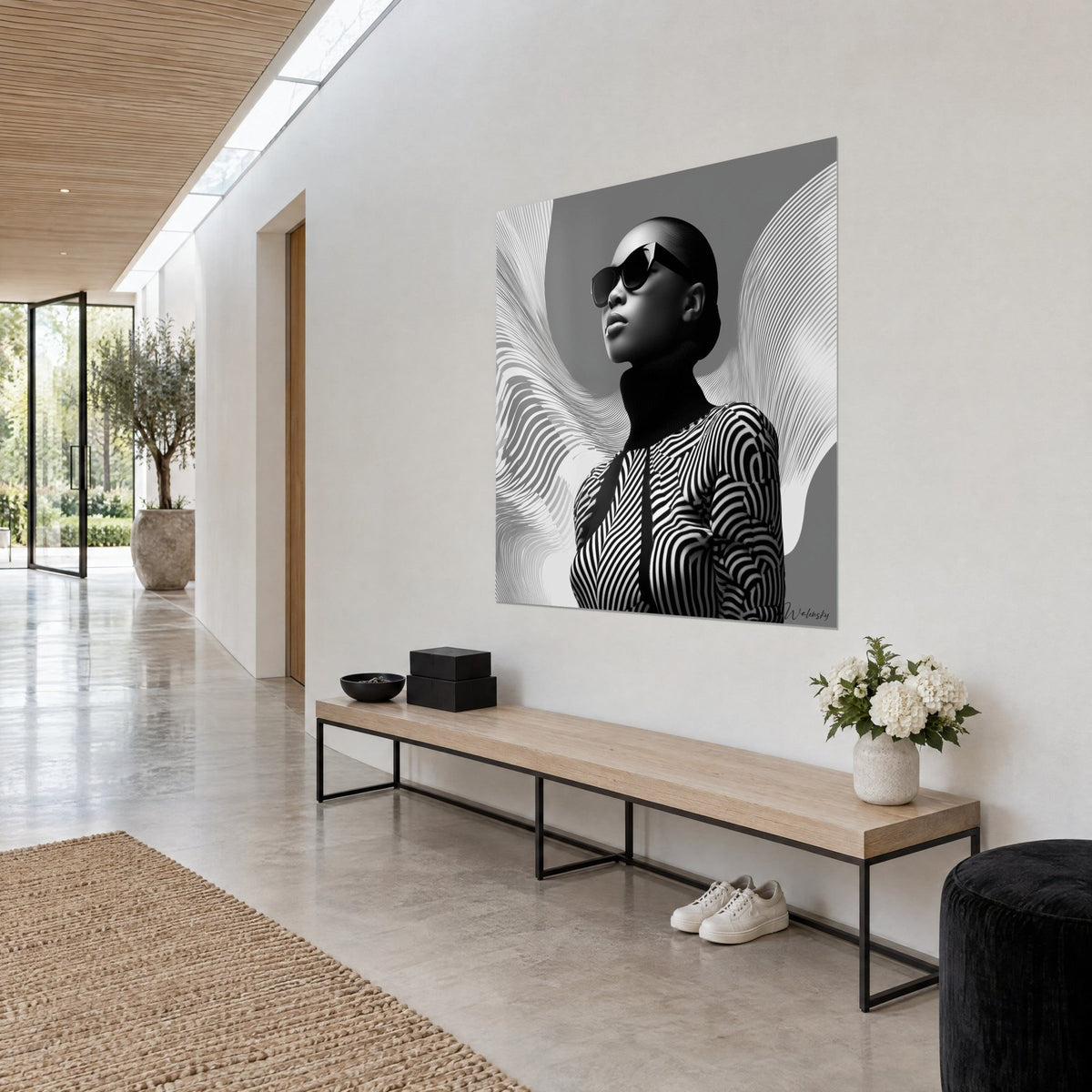Quadro manichino dalla testa rasata e dolcevita nero, onde bianche a ventaglio su sfondo grigio, appeso a una parete chiara accanto a una panca di legno