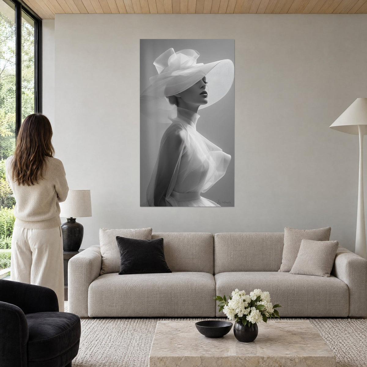 Tableau femme à la capeline de tulle blanc, profil perlé sur fond gris cendré, au-dessus d'un canapé dans un salon lumineux
