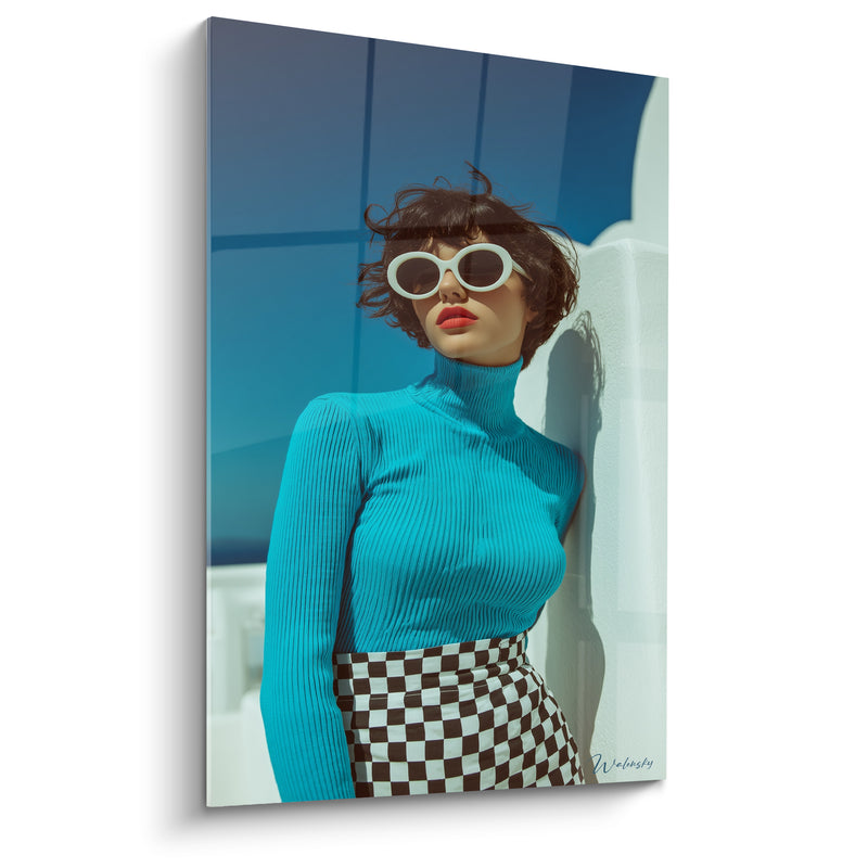 Tableau Femme pull turquoise et jupe damier contre un mur blanc - Cheveux courts au vent - Edition Mode vintage