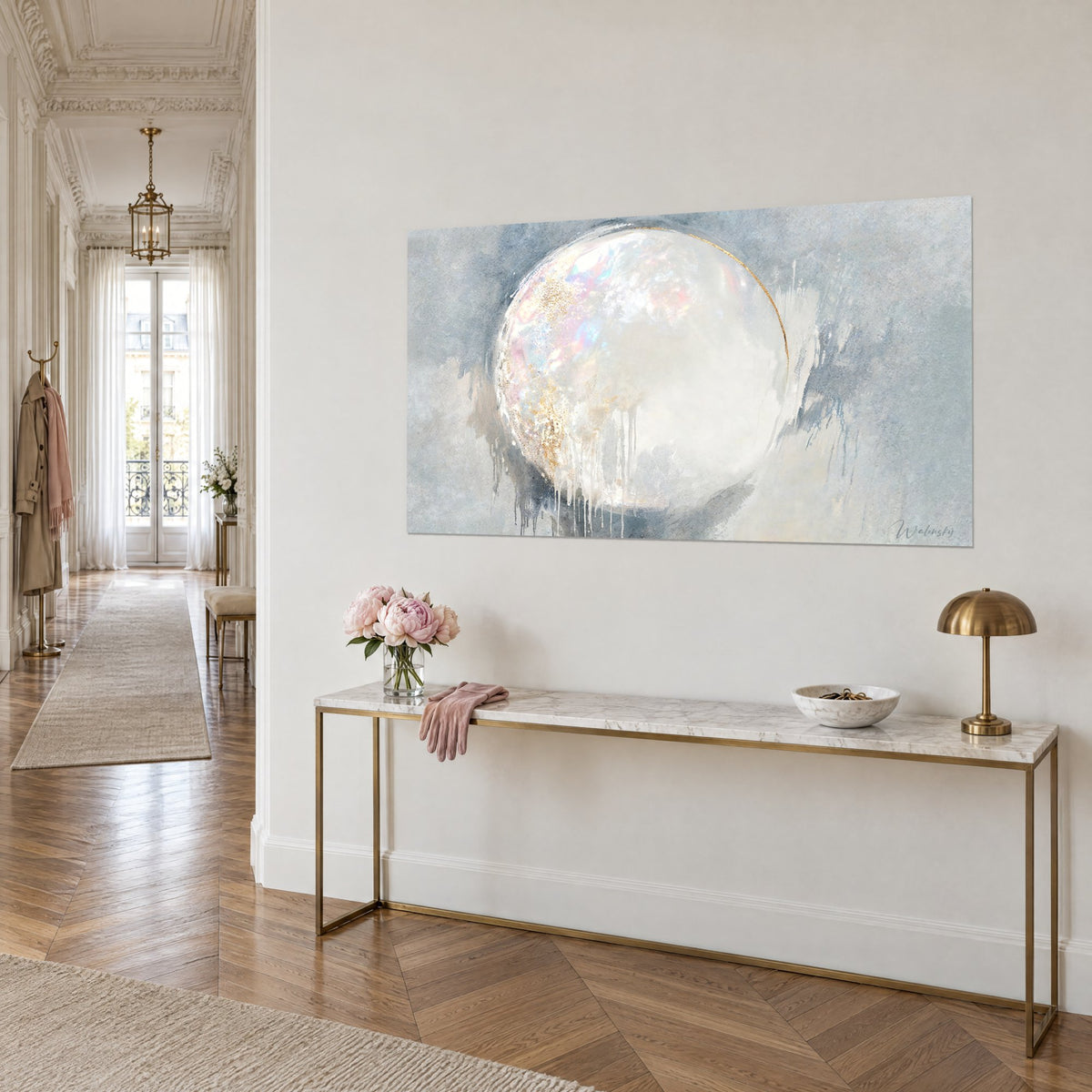 Tableau cercle irisé blanc nacré cerné d'un trait doré, fond gris perle, sur un mur beige près d'une console en laiton