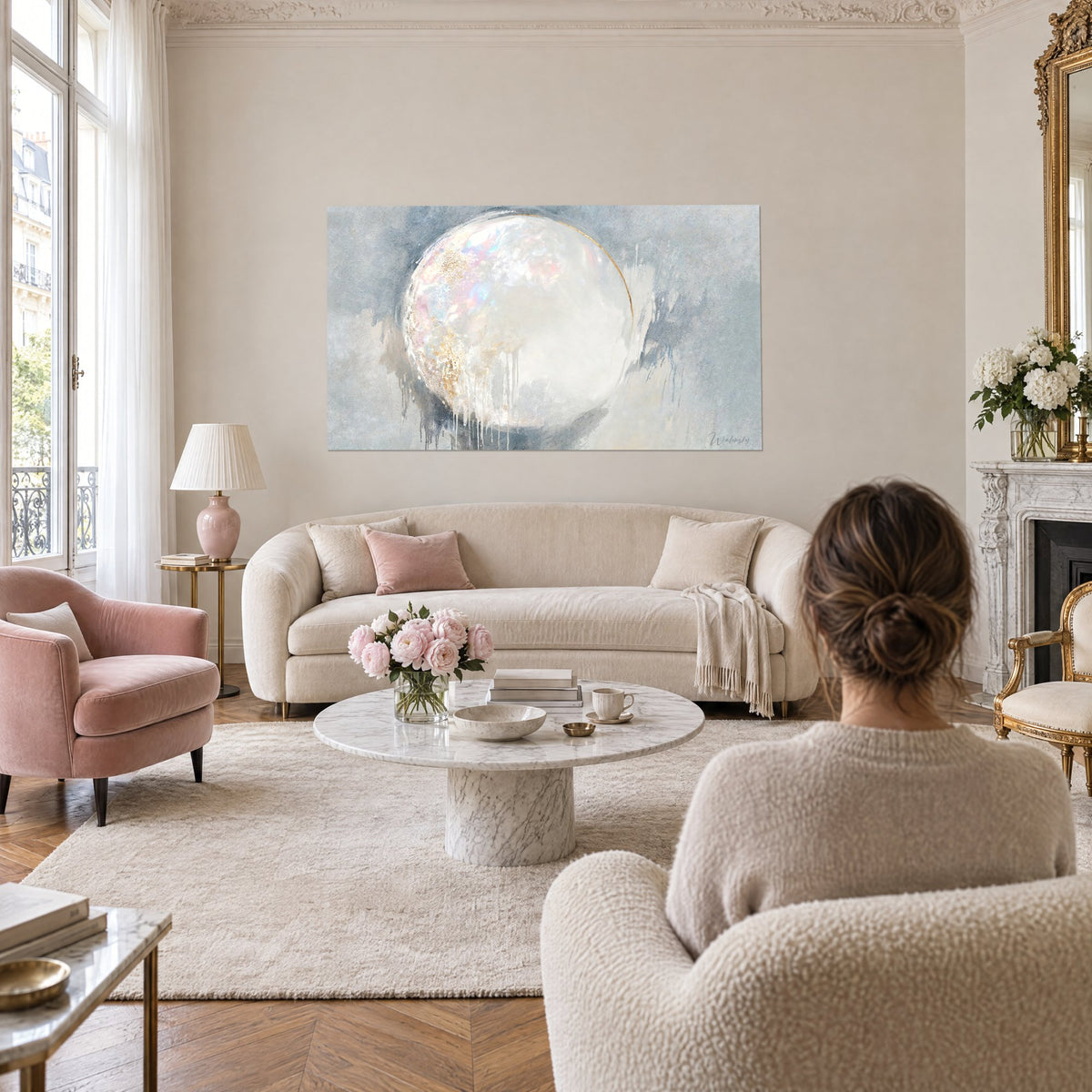 Tableau sphère opaline aux reflets rose et turquoise sur fond gris-bleu, deux personnes de dos, au-dessus d'un canapé dans un salon lumineux