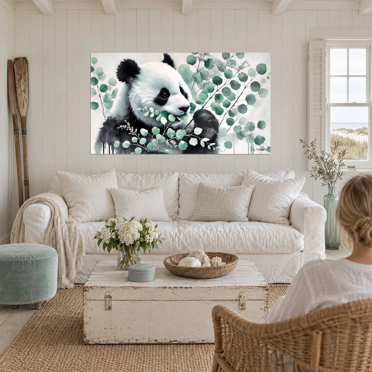 Gemälde Riesenpanda schwarz-weiß, an einem Eukalyptuszweig in Graugrün knabbernd, über einem Sofa in einem hellen Wohnzimmer