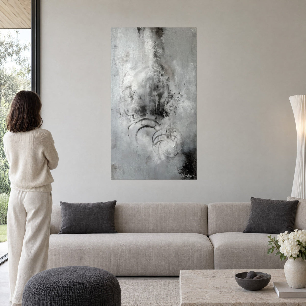Quadro opera astratta monocroma con cerchi tracciati a carboncino, grigio perla e nero carbone, sopra un divano in un soggiorno luminoso