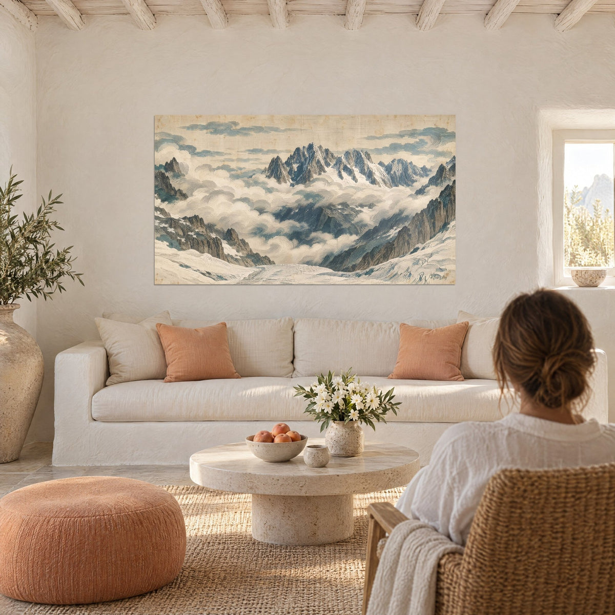 Wall art beige and blue granite needles piercing a sea of clouds, seen from behind by a woman, above a sofa in a bright living room