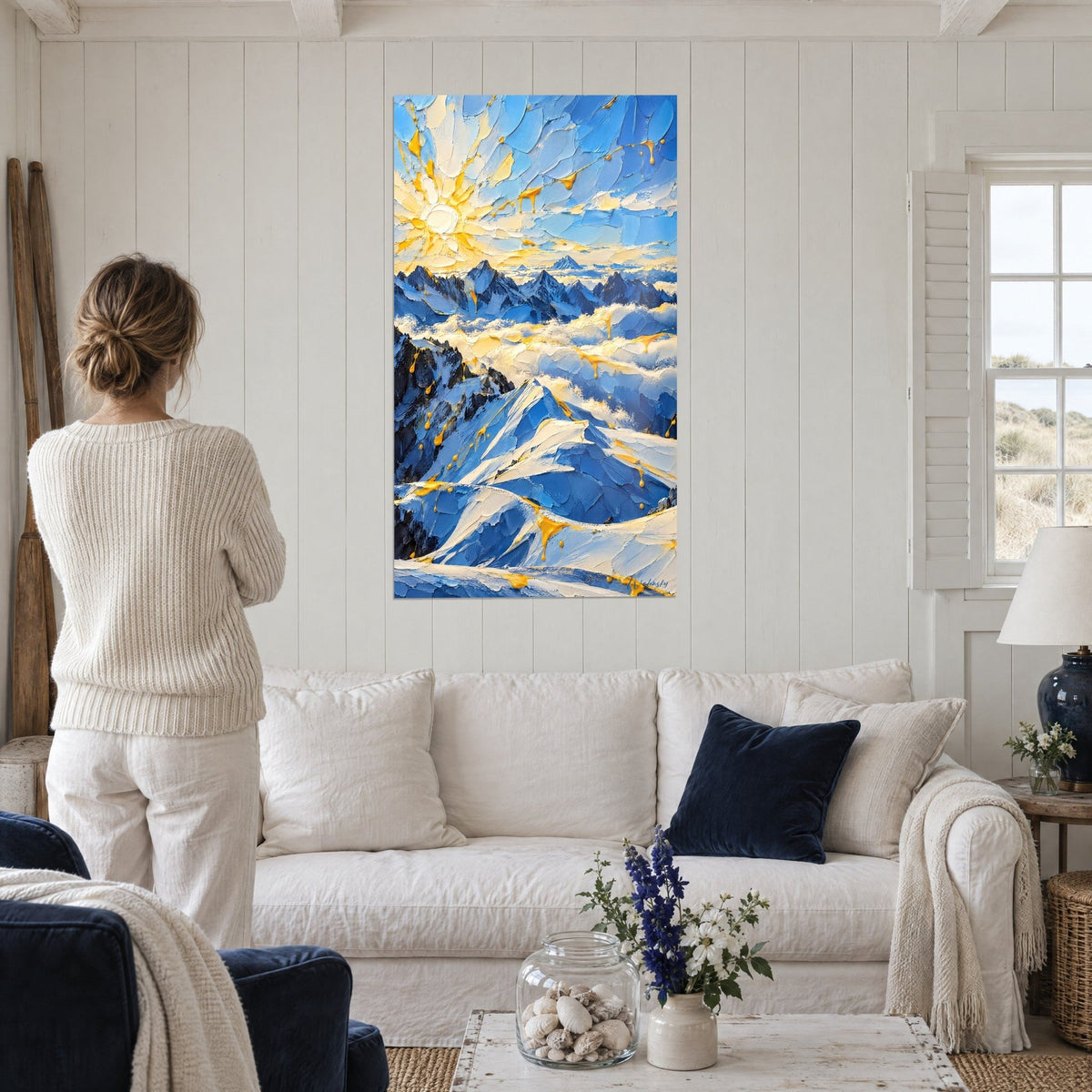 Wall art radiant sun with golden yellow petals over blue snow-capped ridges, above a sofa in a bright living room